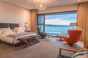 Un dormitorio con una cama y una ventana grande. en Schulphoek Seafront House, en Hermanus
