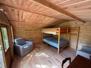 a room with a bunk bed and a chair in a cabin at M'Belles Cabanes in Viala-du-Tarn