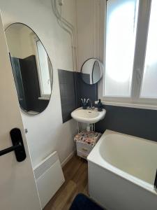 łazienka z umywalką, wanną i lustrem w obiekcie Nice 2 Rooms Full Appartement in Paris w Paryżu
