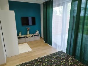 a bedroom with green curtains and a television on a wall at Mieszkanie Wakacyjne Na Wzgórzu in Chmielno