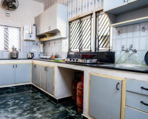 a kitchen with white cabinets and marble counter tops at Mahes Villa - Svenks Hotels in Chennai