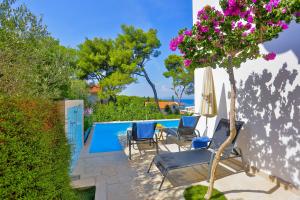 a patio with chairs and a tree next to a swimming pool at Apartments - House Monarch - beach, center & shared pool access in Sutivan