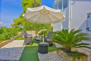 a patio with an umbrella and chairs and a trash can at Apartments - House Monarch - beach, center & shared pool access in Sutivan