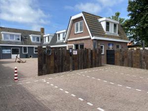 a house with a wooden fence and a brick driveway at Beach Dream 3C in Petten