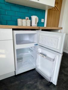 an empty refrigerator with its door open in a kitchen at Brae Cabin in Inverness +4 photos