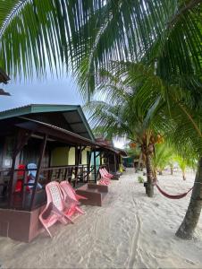 a group of chairs on the beach next to a building at Rainbow Tioman Cottage in Kampong Juara
