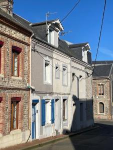 an old brick building with blue shutters on a street at Côte & Mer in Fécamp