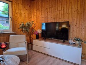 ein Wohnzimmer mit einem Flachbild-TV an einer Holzwand in der Unterkunft Cosy Cottage in Braunfels