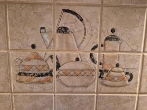 eine geflieste Wand mit vier Teekannen und Pfannen in der Unterkunft Cosy Cottage in Braunfels + 30 Fotos