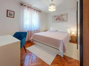 sypialnia z łóżkiem i niebieskim krzesłem w obiekcie Apartment Kraljic by Interhome w mieście Kornić