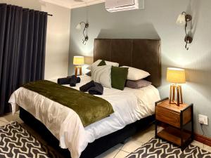 a bedroom with a large bed with two lamps at Fish Eagle Manor in Warmbaths