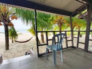 a blue chair sitting on a porch looking at the beach at Rainbow Tioman Cottage in Kampong Juara