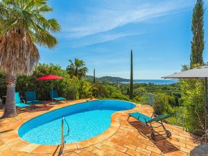 basen z leżakami i parasolami na patio w obiekcie Villa Villa Etoile Filante by Interhome w mieście Le Lavandou