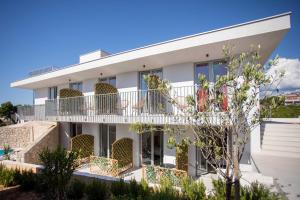 a white building with balconies and plants at Poolside Architect Studios in Novalja