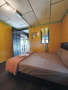 a large bed in a room with yellow walls at Rainbow Tioman Cottage in Kampong Juara