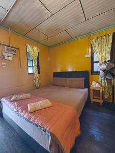 a bedroom with a large bed and two windows at Rainbow Tioman Cottage in Kampong Juara