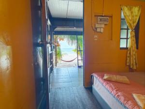 a room with a bed and a door to a beach at Rainbow Tioman Cottage in Kampong Juara