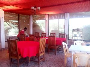 un uomo seduto a un tavolo in un ristorante con tavoli rossi di Miliki Maasai Mara a Maasai Mara National Reserve