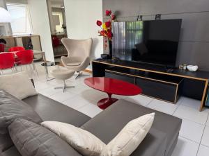 a living room with a couch and a flat screen tv at Cobertura com Piscina no Iloa in Barra de São Miguel