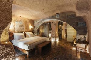 a bedroom with a bed in a room with a stone wall at Millstone Cave Suites Hotel in Uchisar