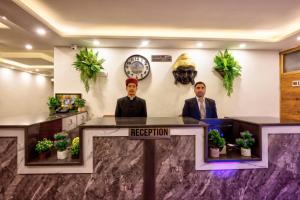 zwei Männer sitzen an einem Rezeptionstresen in einer Lobby in der Unterkunft MRPS Eco Eden Resort nd Spa manali in Manali