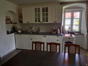 a kitchen with white cabinets and a table and chairs at Chalupa u Jirky in Staré Ransko