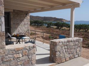 une maison en pierre avec une table et des chaises sur une terrasse dans l'établissement Plakopoules Beach Apartments, à Siteía