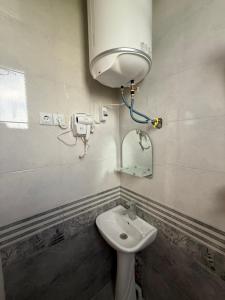 a bathroom with a sink and a water tank at Guest House KHONI in Khoni