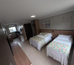 a hotel room with two beds and a kitchen at B14 Suítes in Penha