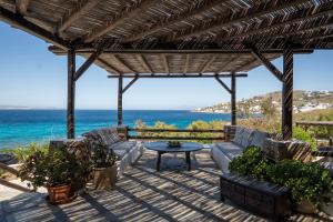 un patio avec une table et des chaises et l'océan dans l'établissement Villa Ipanema with Private Beach by Mykonos Mood, à Mykonos
