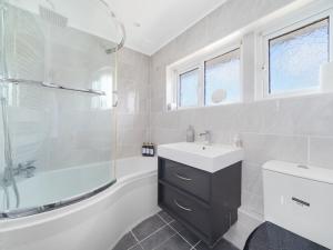 a bathroom with a sink and a tub and a toilet at Pass the Keys Spacious Garden Family House - Marks Gate in Romford +27 photos