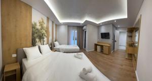 a bedroom with a large white bed and a television at Zena Hotel Durres in Durrës