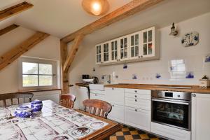 a kitchen with white cabinets and a table with chairs at Landhaus Wusse Ferienwohnung Hiddensee in Ummanz