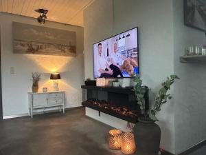 ein Wohnzimmer mit einem Flachbildfernseher an der Wand in der Unterkunft Lichtdurchflutetes Traumhaus 400 Meter zum Strandaufgang, uneinsehbarer Garten mit Terrassenüberdachung, hundefreundlich in Sint Maartenszee