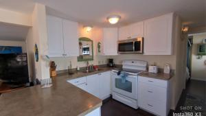 Una cocina con gabinetes blancos y un horno de estufa. en N326 adorable 2 b 2 ba beach bungalow Located on Nettles Island FL, en Jensen Beach