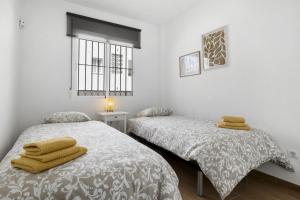 two beds in a white room with towels on them at Carvajal Beach Holiday Apartment in Benalmádena +23 photos