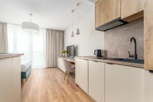 eine Küche mit weißen Schränken und einem Schreibtisch in einem Zimmer in der Unterkunft Jantaris - City Apartments in Mielno