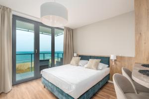 ein Schlafzimmer mit Bett und Blick auf das Meer in der Unterkunft Jantaris - City Apartments in Mielno