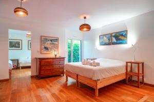 a bedroom with a bed and a dresser and windows at L'Oasis Bretonne - Charmante maison avec piscine in La Trinité-sur-Mer +16 photos