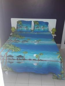 un letto con un copriletto blu con sopra delle palme di Villa spacieuse avec piscine à Le Marin a Le Marin