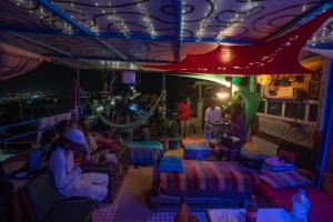 a group of people sitting at tables under a tent at night at Agachill Surf House in Tamraght Ouzdar