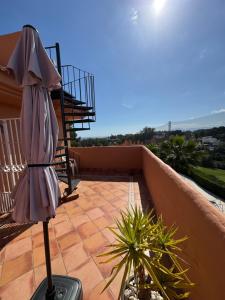 a patio with an umbrella on a balcony at Marbella Deluxe Rooms in Royal Cabopino Townhouse in Marbella