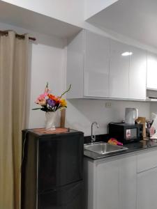 La cuisine est équipée d'un évier et d'un vase de fleurs sur le réfrigérateur. dans l'établissement Sea Residences Ace, à Manille