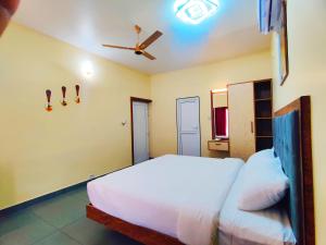a bedroom with a white bed and a ceiling fan at Pakalakam Resort in Cheruppulasseri +36 photos