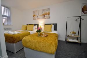 a bedroom with two beds and a table with flowers on it at Gosford Park Studio 2 - Coventry in Coventry