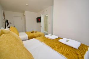 two beds in a room with yellow and white at Gosford Park Studio 2 - Coventry in Coventry