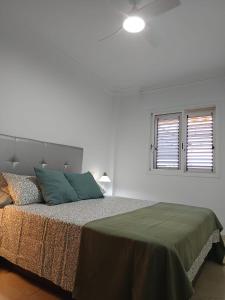 a white bedroom with a bed with a green blanket at alquilaencanarias Candelaria, Terrace and Pool ! in Candelaria
