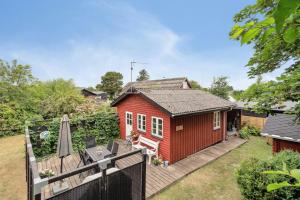 a red tiny house with a deck and an umbrella at Lifestyle Near Sea And Town in Nykøbing Mors