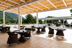 a patio with tables and chairs and mountains in the background at AH Premium Baia dei Faraglioni in Mattinata