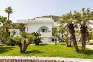 a white house with palm trees in front of it at AH Premium Baia dei Faraglioni in Mattinata